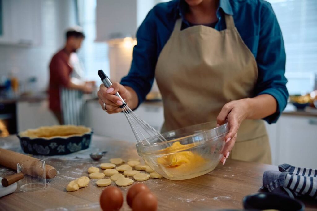 Close up of woman whisking eggs while baking in the kitchen.